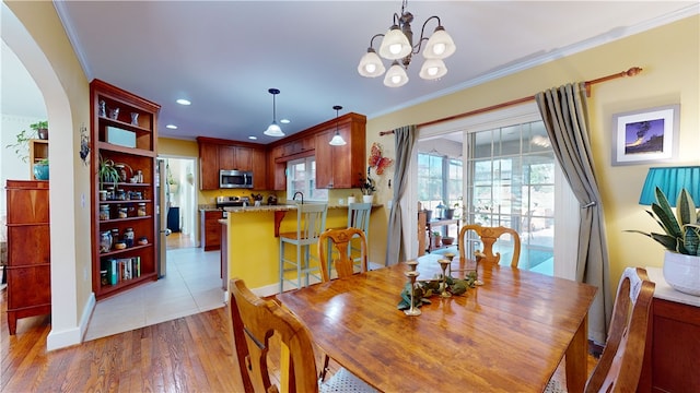 dining area with arched walkways, crown molding, recessed lighting, and wood finished floors