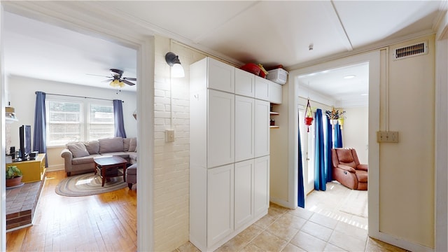 hallway featuring light wood-type flooring, visible vents, and crown molding