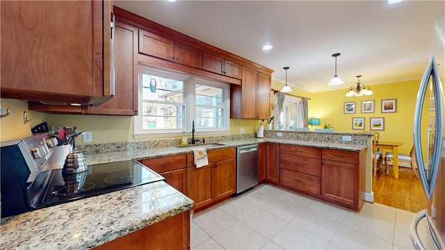 kitchen featuring hanging light fixtures, appliances with stainless steel finishes, a sink, light stone countertops, and a peninsula