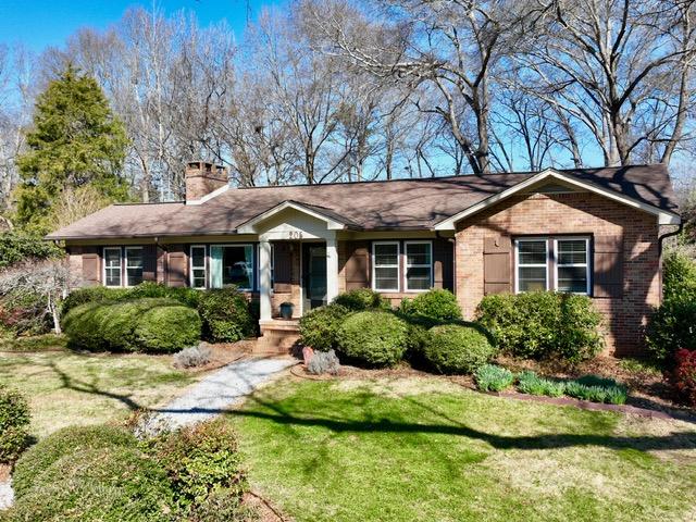 ranch-style house with brick siding, a front lawn, and a chimney