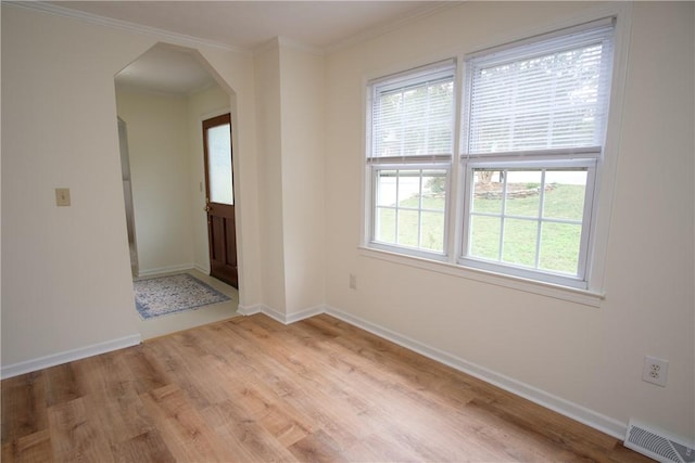 unfurnished room featuring light wood finished floors, baseboards, visible vents, and arched walkways