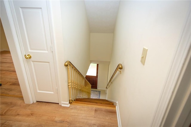 stairway with wood finished floors and baseboards