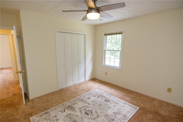 unfurnished bedroom featuring a textured ceiling, a ceiling fan, baseboards, a closet, and carpet