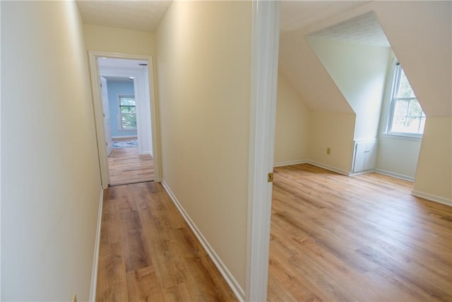 corridor featuring baseboards and light wood finished floors