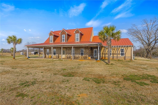 farmhouse featuring metal roof, stone siding, a front lawn, and a standing seam roof