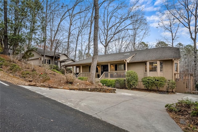 ranch-style home with covered porch and roof with shingles