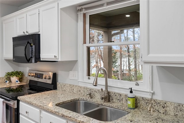 kitchen with electric range, black microwave, white cabinets, and a sink