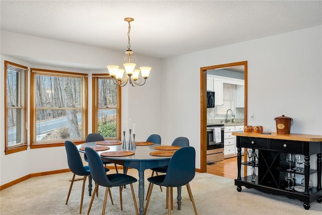 dining room featuring baseboards, a textured ceiling, a chandelier, and light colored carpet