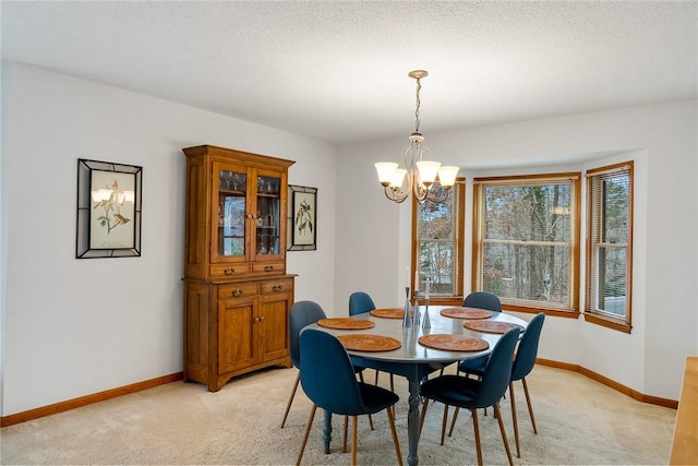 dining room with a chandelier, light colored carpet, a textured ceiling, and baseboards