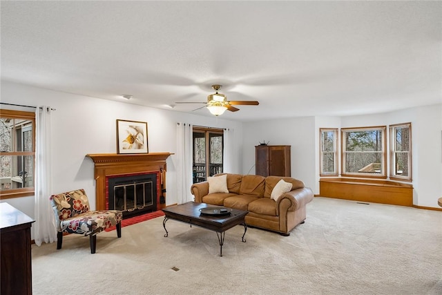 carpeted living room featuring a fireplace with flush hearth and a ceiling fan