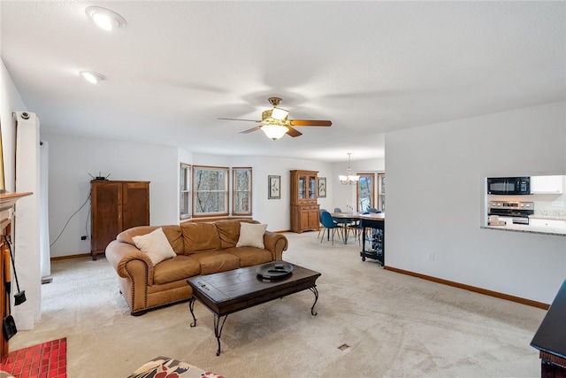 living room with light carpet, baseboards, and ceiling fan with notable chandelier