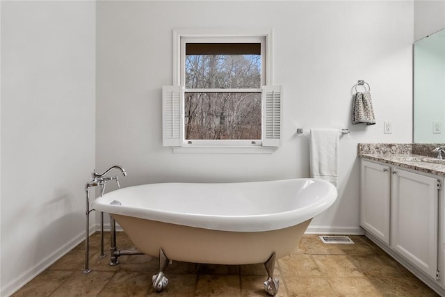 bathroom with a soaking tub, visible vents, vanity, and baseboards