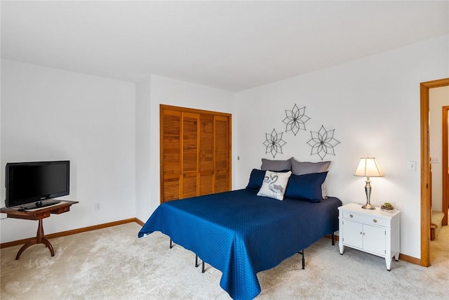 bedroom featuring a closet, light carpet, and baseboards