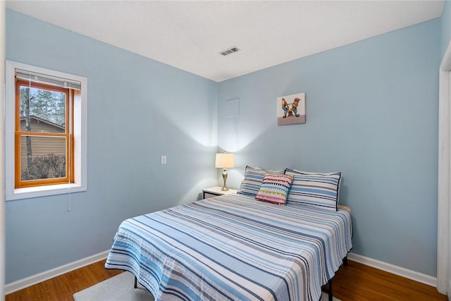 bedroom featuring visible vents, baseboards, and wood finished floors