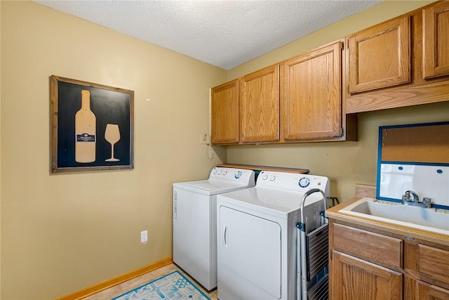 laundry room featuring cabinet space, baseboards, a textured ceiling, separate washer and dryer, and a sink