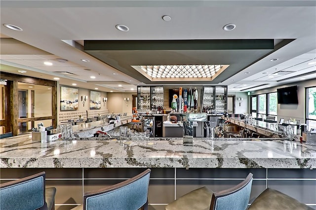 kitchen featuring stone counters, a raised ceiling, and open floor plan