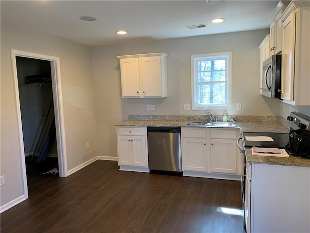 kitchen with stainless steel appliances, dark wood-type flooring, a sink, and visible vents