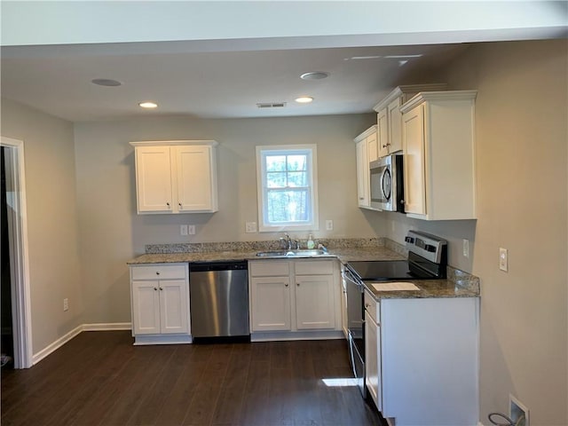 kitchen with visible vents, dark wood finished floors, stainless steel appliances, white cabinetry, and a sink