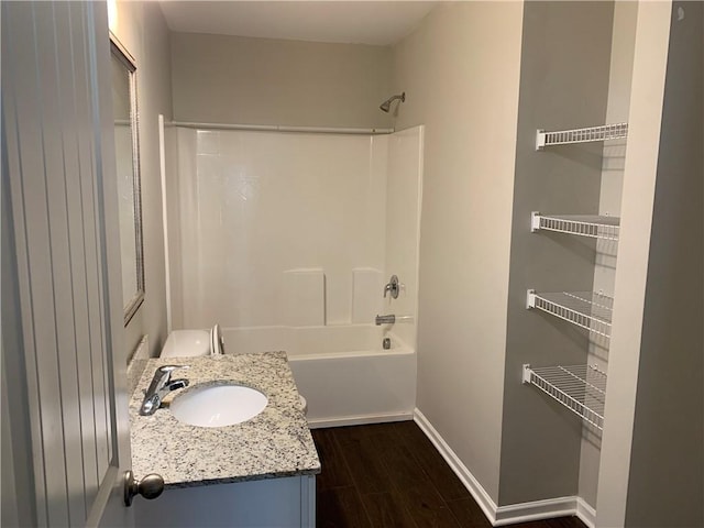 full bathroom featuring washtub / shower combination, baseboards, wood finished floors, and vanity