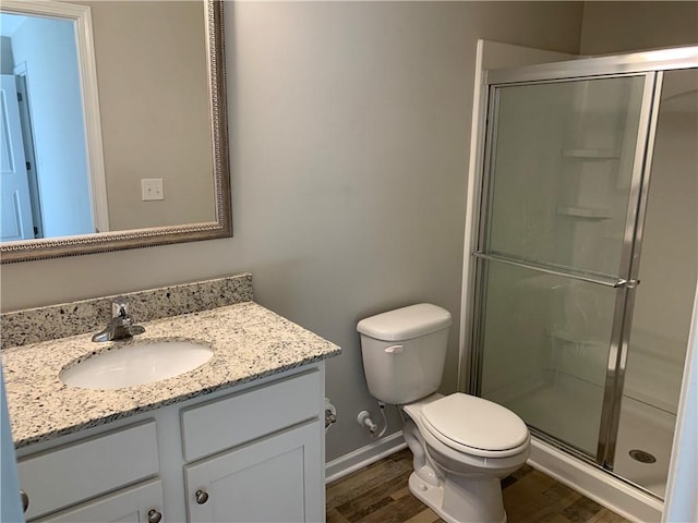 full bathroom featuring toilet, wood finished floors, vanity, baseboards, and a shower stall