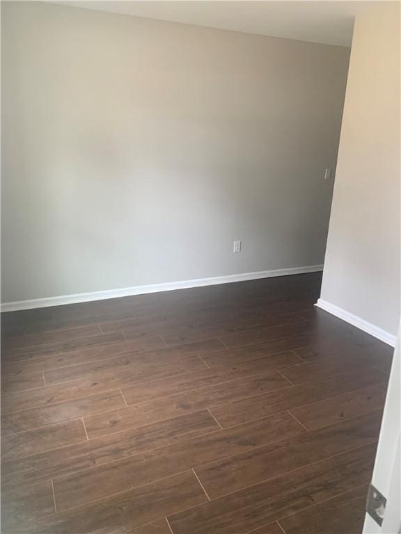 spare room featuring dark wood finished floors and baseboards