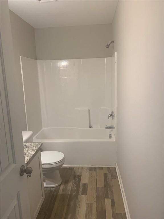 bathroom with toilet, shower / washtub combination, wood finished floors, and vanity