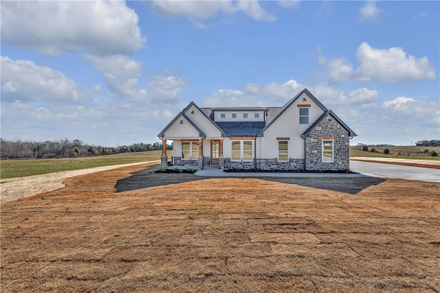 view of front of property featuring stone siding, a front lawn, and a porch