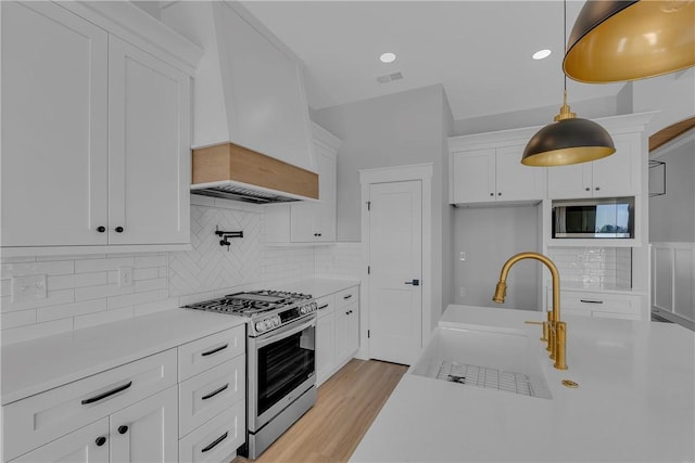 kitchen featuring visible vents, white cabinets, stainless steel appliances, light countertops, and a sink