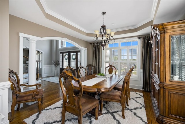 dining space with a chandelier, plenty of natural light, a raised ceiling, and decorative columns