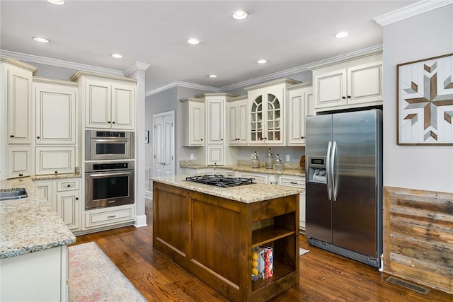 kitchen featuring light stone counters, visible vents, stainless steel appliances, and dark wood-type flooring