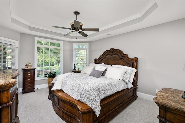 bedroom with light carpet, baseboards, a raised ceiling, a ceiling fan, and ornamental molding