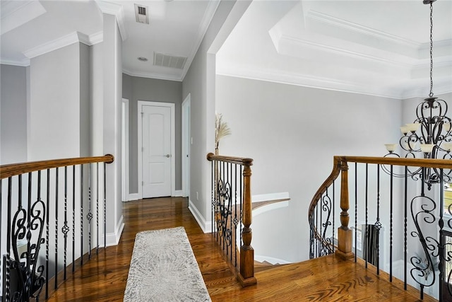 hall featuring visible vents, wood finished floors, an inviting chandelier, crown molding, and an upstairs landing