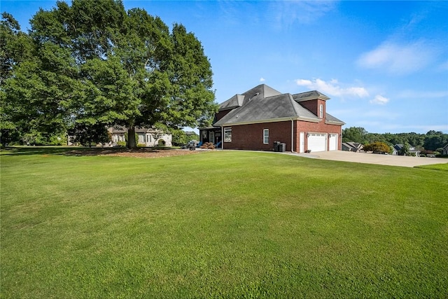 view of side of property featuring concrete driveway, a lawn, an attached garage, central AC, and brick siding