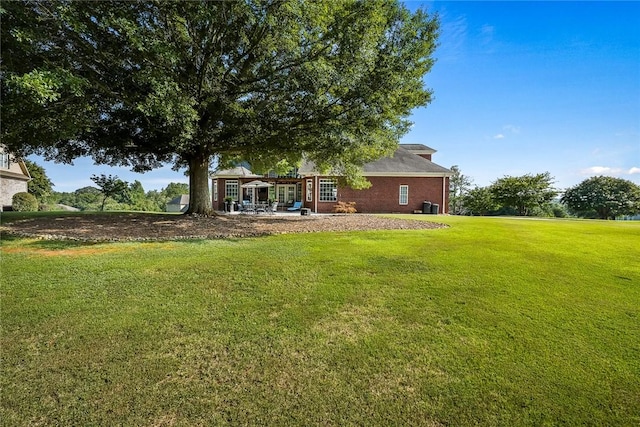 rear view of property featuring brick siding, a patio, and a yard