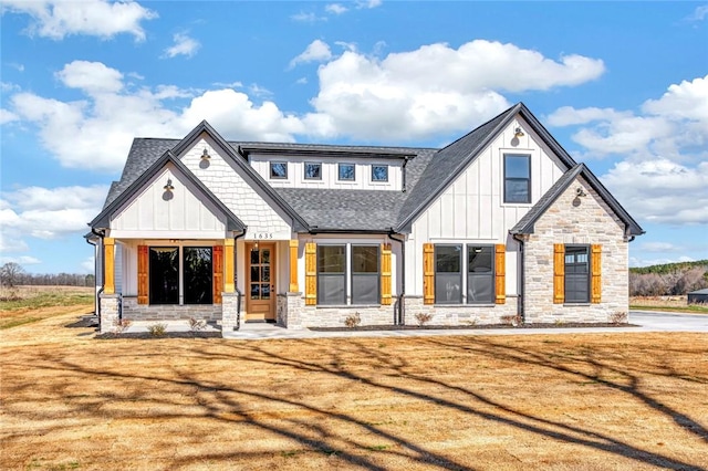 modern inspired farmhouse featuring board and batten siding, a front yard, stone siding, and roof with shingles