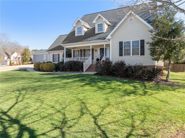 new england style home featuring a shingled roof, a front lawn, and a porch