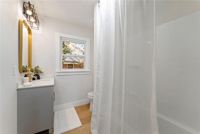 full bathroom featuring curtained shower, toilet, wood finished floors, vanity, and baseboards