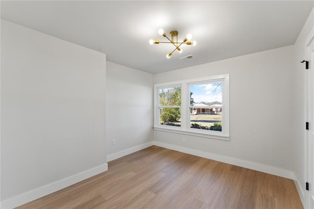 unfurnished room with baseboards, light wood-style floors, visible vents, and an inviting chandelier