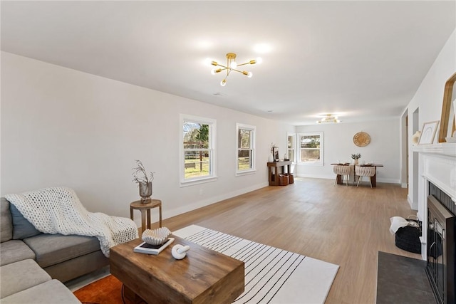 living area with a fireplace with flush hearth, light wood-style flooring, and baseboards