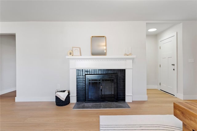 living area with a brick fireplace, baseboards, and wood finished floors