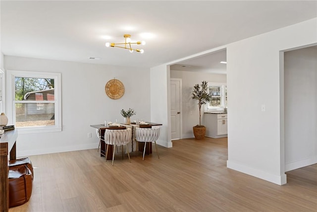 dining room with a chandelier, baseboards, and light wood finished floors