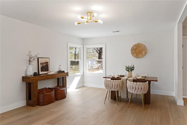 dining room featuring visible vents, light wood-style flooring, baseboards, and an inviting chandelier