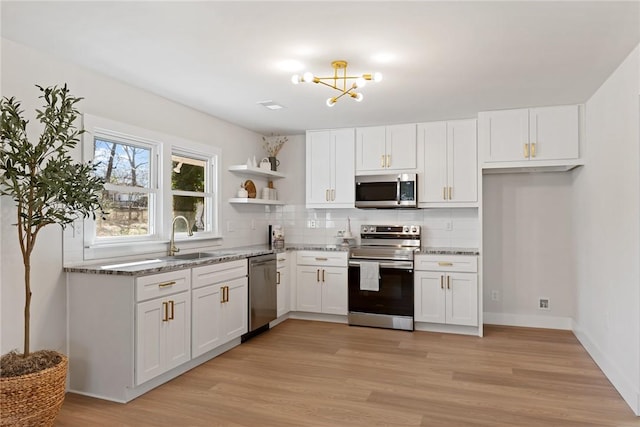 kitchen with open shelves, appliances with stainless steel finishes, a sink, and white cabinets