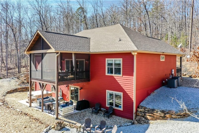 view of side of home with a shingled roof, a sunroom, a patio area, and central AC unit