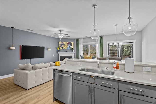 kitchen with gray cabinetry, light wood-style flooring, a sink, stainless steel dishwasher, and open floor plan