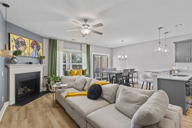 living area with light wood-type flooring, a fireplace with flush hearth, baseboards, and a ceiling fan