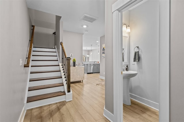 stairway featuring wood finished floors, visible vents, and baseboards