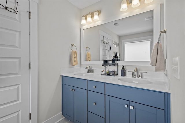 bathroom featuring double vanity, visible vents, baseboards, and a sink