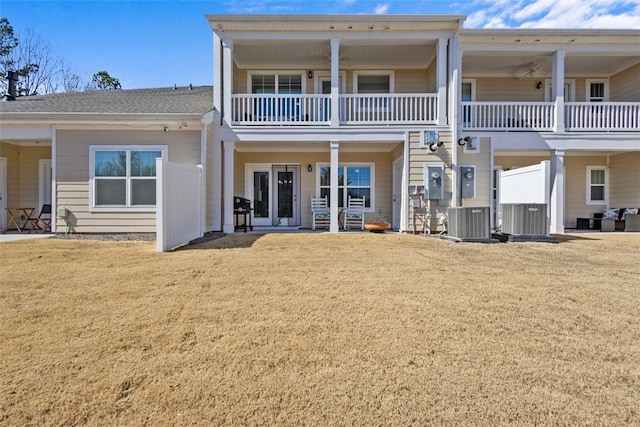 rear view of property with cooling unit and a lawn