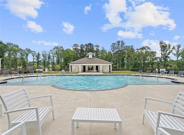 community pool with a patio area and fence